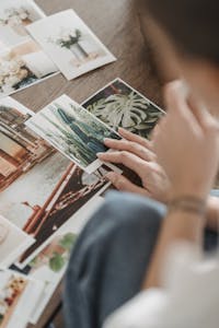 A person choosing various photographs from a diverse and artistic collection on a table.
